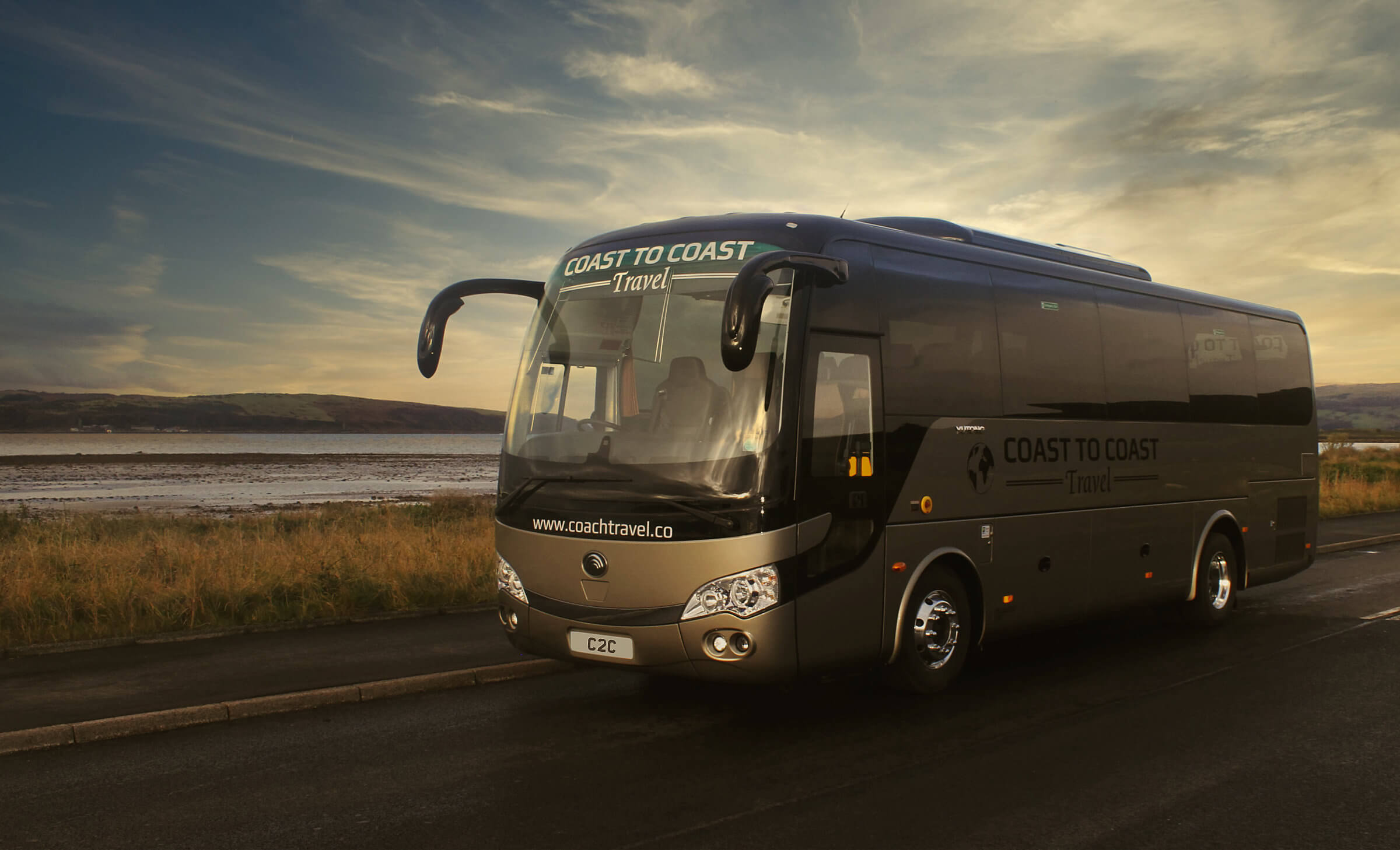 Coast to Coast coach parked by the roadside with the coastline in the distance